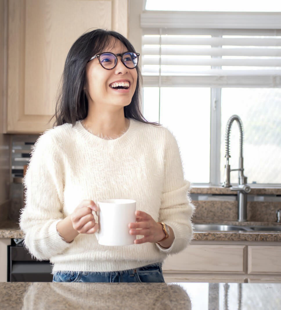 Laci Le smiles while holding a coffee cup in her kitchen